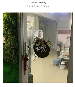 Detail of hello welcome sign on glass door with floral bow and green plants