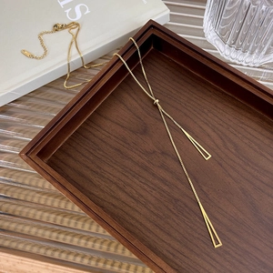 Detail of 18k gold plated titanium steel triangle necklace in a wooden tray