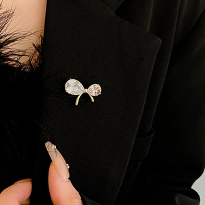 Detail of elegant gold-plated bow brooch with sparkling crystals on a black suit blazer
