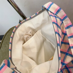 Close-up of pink and blue plaid canvas bag interior with inner pocket and zipper closure