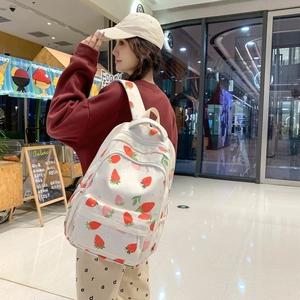 Close-up of strawberry print backpack with multiple zippers on female model