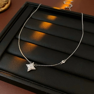 Détail d'un collier étoile en argent avec zircons sur un plateau à bijoux noir