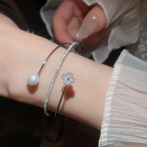 Detail of three-layer silver bangle with pearl, pave diamonds and clover motif
