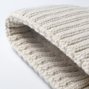 Detailed macro view of a stylish beige ribbed knitted hat with warm fleece lining