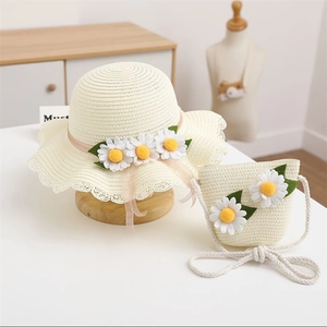 Detail of straw sun hat and matching bag set with white daisy flowers and lace trim