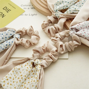 Detail of four floral satin scrunchies with ribbons in blue, yellow, red, and green prints