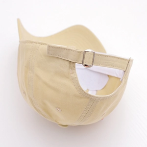 Detail of adjustable silver metal buckle and cotton twill fabric on the beige kids' cap