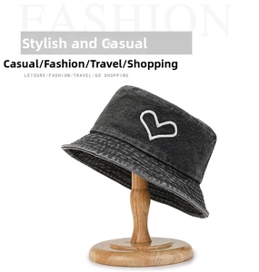 Detailed view of white heart embroidery on a black washed denim bucket hat for women