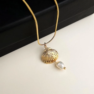 Close-up of gold shell pendant and baroque pearl on a 18K plated stainless steel chain