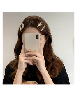 Mirror selfie showing a set of four acetate hair clips in pearl white and tortoiseshell pattern