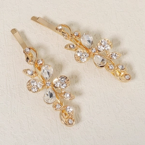 Detail of gold floral hair clips featuring delicate rhinestones and metallic leaf patterns