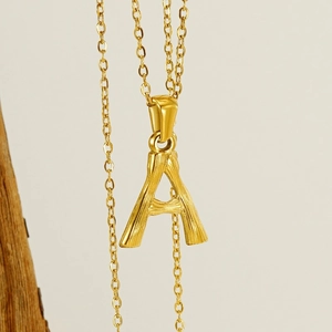 Close-up of golden letter A pendant necklace in stainless steel with a fine chain link