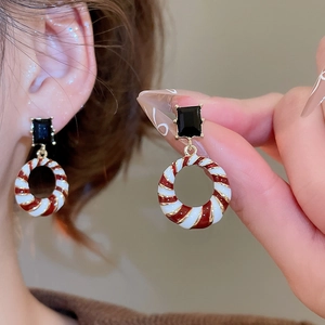 Detail of geometric drop earrings with red and white enamel spirals and black gemstones