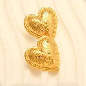 Macro detail of heart-shaped gold stud earring featuring 3D snake motif and hammered texture