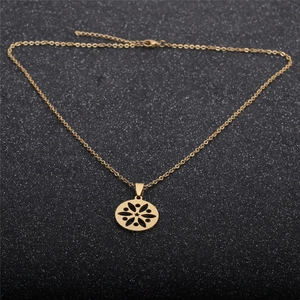 Collana dorata in acciaio inossidabile con ciondolo a fiori traforato su sfondo scuro