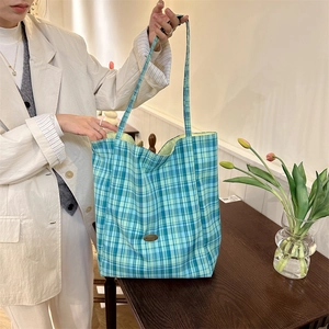 Detailed view of the teal checkered tote bag carried by a model for a casual daily look