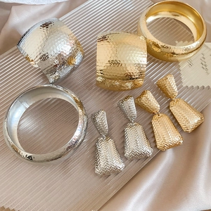 Detail showing textured gold and silver metal bangles and earrings on a tray