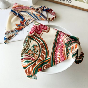 Macro view of silky paisley headbands with elastic bands on a minimalist white desk