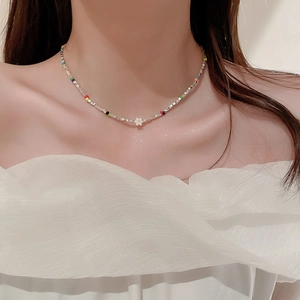 Gros plan du collier fleur perlé avec touches colorées sur femme en haut à épaules nues