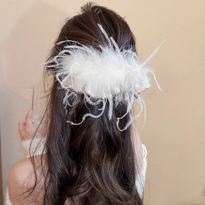 Detailed view of large white fluffy feather hair claw clip on dark wavy hair