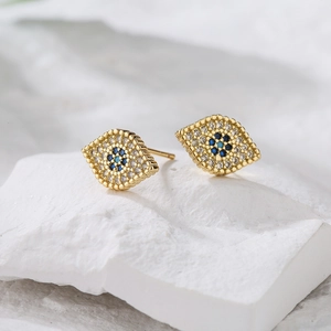 Detailed macro view of gold-plated eye earrings with blue and white zircon stones