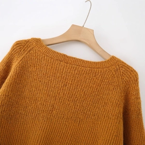 Orange-brown knitted crew neck sweater with thick textured wool on wooden hanger