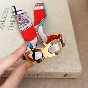 Close-up of golden hollow metal cuff bracelet wrapped in colorful patterned silk fabric