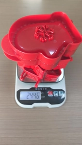 Macro shot of red 3D Christmas tree cookie molds with snowflake patterns on a digital scale