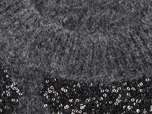 Detalle de punto de felpa gris con ribete de lentejuelas negras y textura de fibra suave