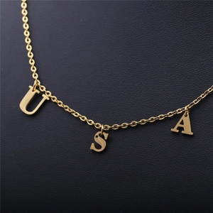 Collier élégant avec lettres USA dorées présenté sur une surface en cuir noir