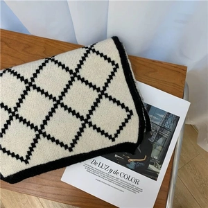 Detailed texture of a classic plaid knitted scarf featuring a black and beige argyle pattern