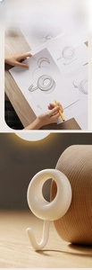 Detail of cream white adhesive J-hook with polished finish on a warm wooden background