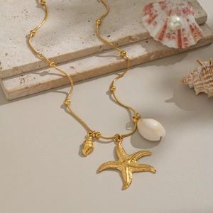Golden starfish pendant necklace with natural sea shell charms on beach style background