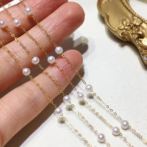 Detail of 18k gold double-layer chain with natural pearls on a soft background