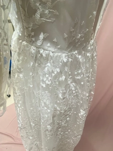 Intricate white lace embroidery detail with shimmering sequins on bridal gown sleeves