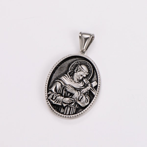 Macro detail of silver oval pendant featuring a 3D embossed religious figure holding a cross