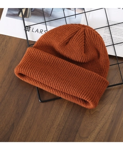 Close-up of caramel knit beanie with neat ribbed texture on a rustic wooden background