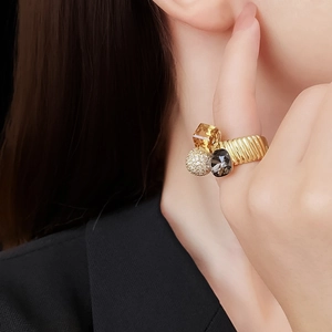 Detailed side view of gold-plated ring with yellow crystals and pave ball on finger