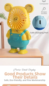 Detail showing the USB charging port on a yellow bear mini fan sitting on a wood surface