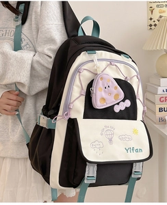 Detail of black and white school backpack featuring purple pouch and colorful embroidery
