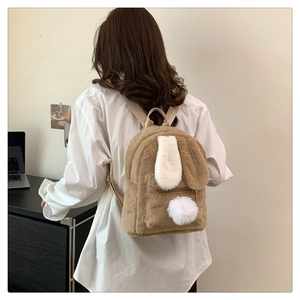 Detail view of a fluffy plush bunny ear backpack with long fur and soft pom-pom accents
