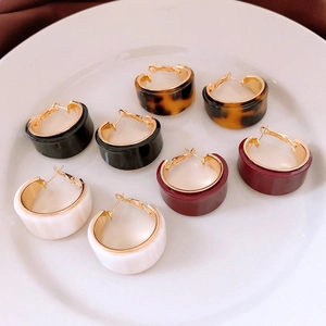 Close-up of four pairs resin C-hoop earrings in black marble amber and burgundy colors