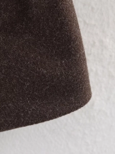Close-up of thick dark brown wool fabric texture and material detail on the winter coat