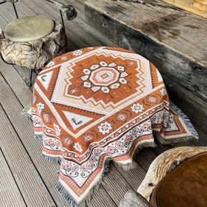 Close-up of bohemian woven blanket with geometric patterns and fringe detail on wood