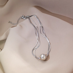 Detail of silver layered snake chain necklace with a matte metallic sphere pendant