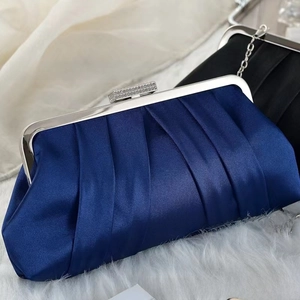 Close-up of pleated satin evening bags with rhinestone clasp and silver chain strap