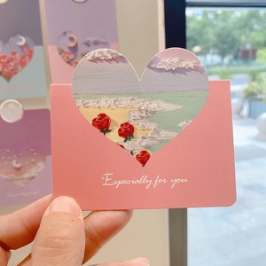 Close-up of pink greeting card with heart cutout and rose beach oil painting detail