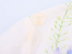 Detailed close-up of floral embroidery on beige cotton-linen dress fabric