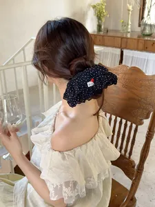 Detail of black polka dot scrunchie with red heart button on a woman's hair
