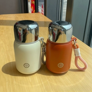 Detail of cream and orange stainless steel flasks with mirror lids and woven straps